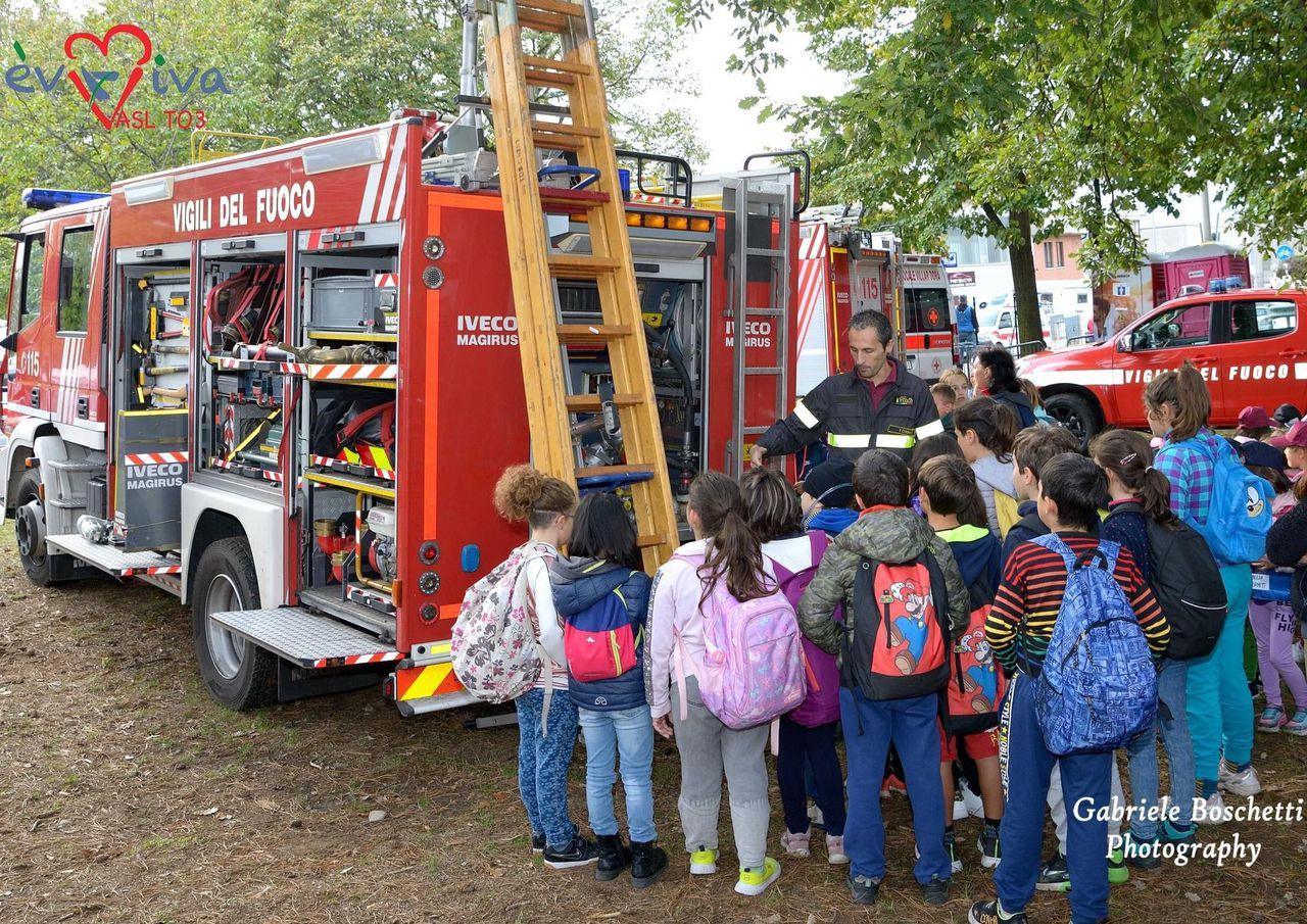 Bambini incuriositi accanto ai Vigili del Fuoco durante una giornata di prevenzione EVVIVA